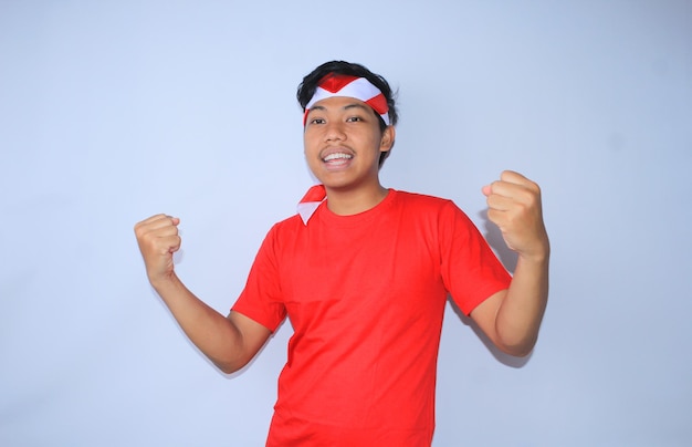 un indonésien excité célèbre sa réussite avec un geste oui portant un t-shirt rouge et un bandeau