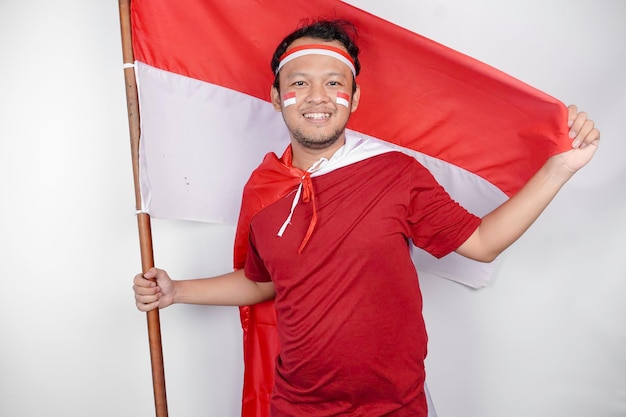 Photo un indonésien heureux et souriant tenant le drapeau d'indonésie39 pour célébrer le jour de l'indépendance de l'indonèse isolé sur un fond blanc