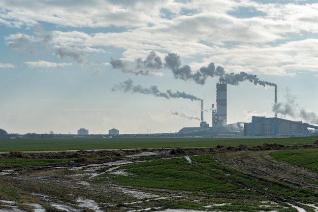 Industrie chimique Pollution de l'environnement par des émissions nocives dans l'atmosphère La fumée toxique provient des gros tuyaux L'usine empoisonne la nature Silhouette de tuyaux et de fumée Journée ensoleillée