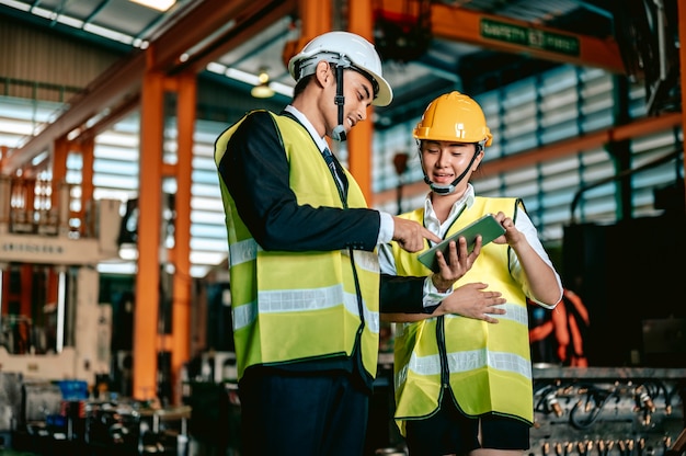 Industrie de l'ingénieur femme asiatique portant un casque et tenant une liste de contrôle debout dans la zone de la machine