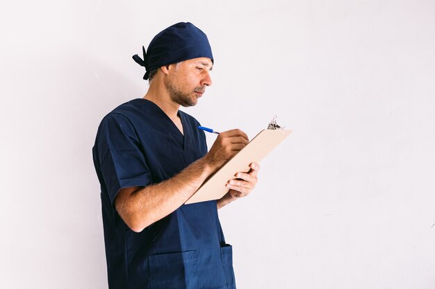 Infirmier, médecin ou vétérinaire en uniforme bleu à la fenêtre d'un hôpital, rédigeant un rapport. Concept de médecine, d'hôpital et de soins de santé.