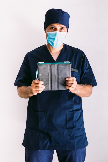 Infirmier, médecin ou vétérinaire en uniforme bleu à la fenêtre d'un hôpital, regardant une tablette. Concept de médecine, d'hôpital et de soins de santé.