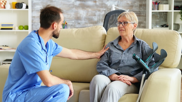 Infirmier parlant avec une vieille femme souffrant de parkinson dans une maison de soins infirmiers