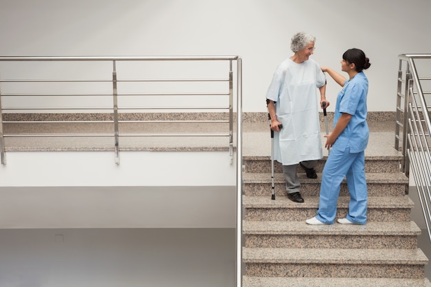 Infirmière aidant une dame âgée descendre les escaliers