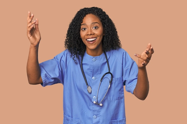 Une infirmière américaine d'origine africaine dans le fond du studio reçoit une agréable surprise excitée et lève la main.