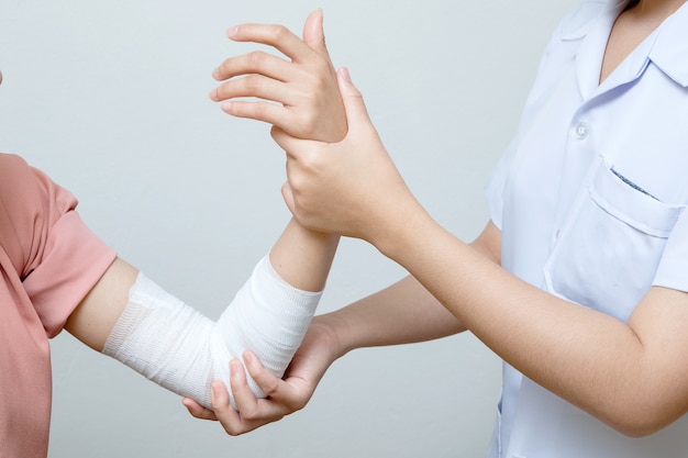 Infirmière appliquant un bandage au patient blessé au coude