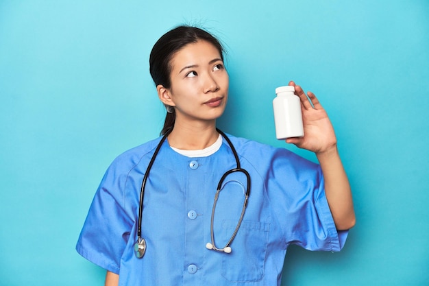 Infirmière asiatique avec une bouteille de pilules prise en studio