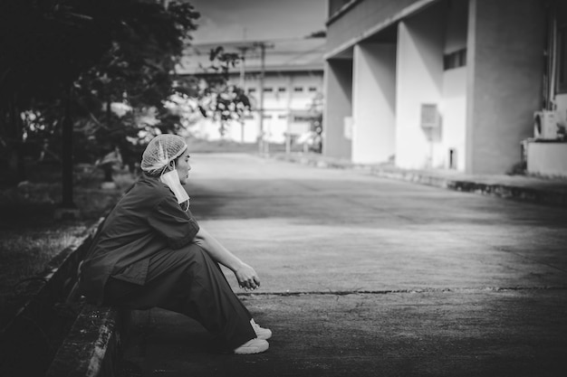 Une infirmière asiatique fatiguée et déprimée porte un masque facial uniforme bleu assis sur le sol de l'hôpital Jeune femme médecin stressée par le travail acharné