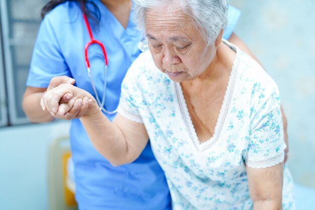 Infirmière asiatique, kinésithérapeute soignant, aidant et soutenant une patiente âgée ou âgée.