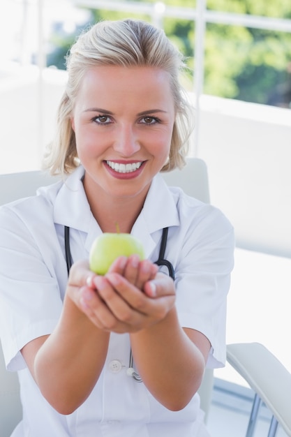 Infirmière blonde tenant une pomme verte