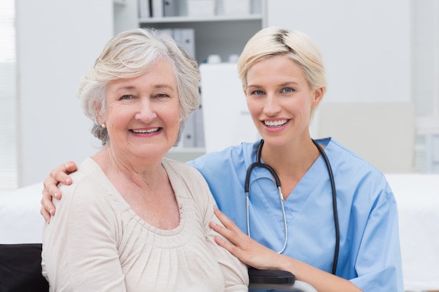 Infirmière avec bras autour de patient senior en clinique