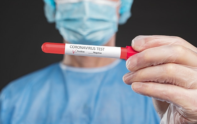 Infirmière de culture montrant un tube avec un test de coronavirus positif