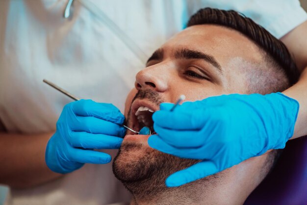 Infirmière dentiste vérifiant la bouche du patient analysant l'infection des dents à l'aide d'un instrument de forage stomatologique lors d'un examen orthodontique dans la salle du cabinet dentaire. Concept de procédure de dentisterie. Haute qualité