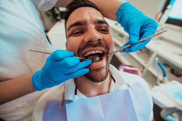 Infirmière dentiste vérifiant la bouche du patient analysant l'infection des dents à l'aide d'un instrument de forage stomatologique lors d'un examen orthodontique dans la salle du cabinet dentaire. Concept de procédure de dentisterie. Haute qualité