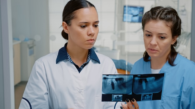 Infirmière en dentisterie et stomatologue examinant l'analyse de la dentition