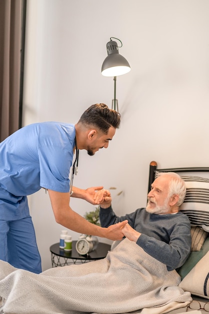 Infirmière à domicile aidant le patient à se mettre en position assise