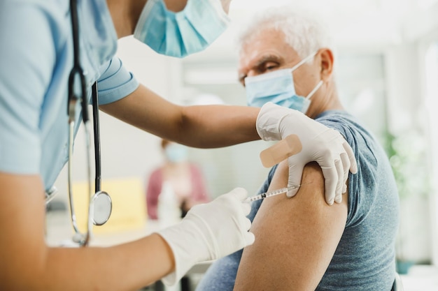 Une infirmière donnant un vaccin à un homme âgé en raison d'une pandémie de coronavirus.