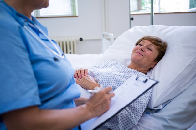 Photo infirmière écrit sur le presse-papiers tout en interagissant avec un patient