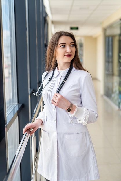 Infirmière expérimentée en blouse blanche regardant la caméra avec un sourire tout en posant