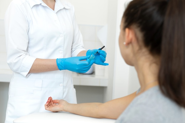 Une infirmière gantée retire une aiguille stérile de son emballage devant le patient