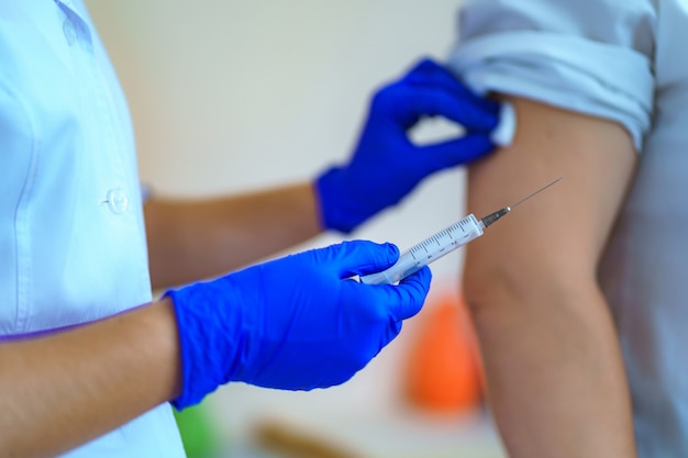 Infirmière en gants faisant vacciner le patient dans une chambre d'hôpital pendant l'épidémie de grippe et de rougeole. Vaccin antigrippal, protection et prévention des maladies infectieuses virales