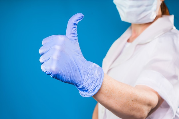 L'infirmière avec des gants montre le pouce vers le haut, isolée