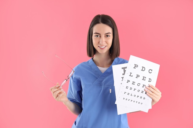 Infirmière avec lunettes et test de vision sur fond rose