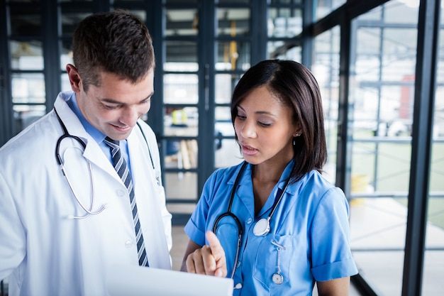 Infirmière et médecin examinant des dossiers dans le couloir