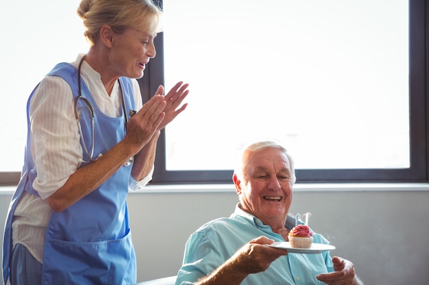 Infirmière et senior homme fête son anniversaire avec muffin