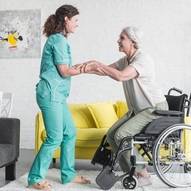 Infirmière souriante aidant une patiente âgée à sortir du fauteuil roulant