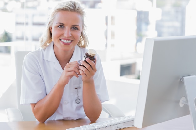 Infirmière souriante assise derrière un bureau