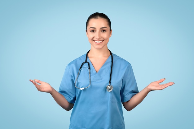 Une infirmière souriante avec les paumes ouvertes dans un uniforme bleu