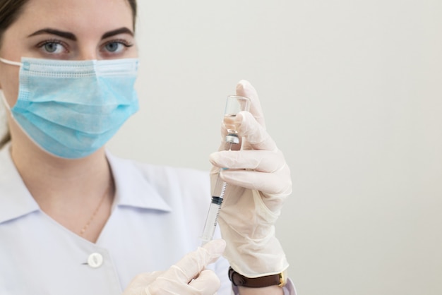 infirmière travailleur médical close up dans des masques et des gants avec une seringue dans ses mains se préparant à donner une injection