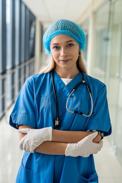 Infirmière En Uniforme Avec Un Chapeau Sur La Tête Avec Un Stéthoscope Et  Des Gants Se Tient Dans Le Couloir