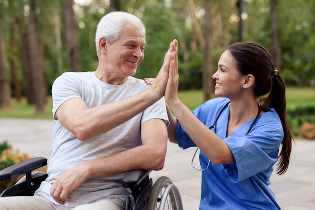 Une infirmière et un vieil homme en fauteuil roulant ont cinq ans.