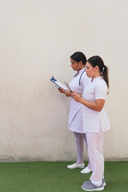 Infirmières latines utilisant une tablette numérique dans le couloir de l'hôpital