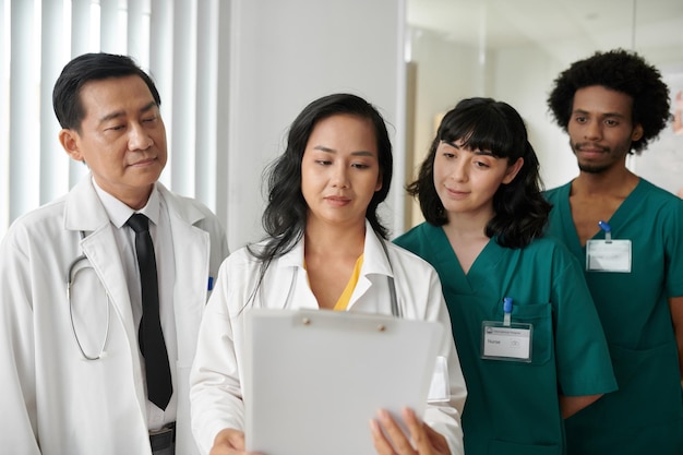 Photo infirmières et médecins lisant un document contenant des informations sur les nouveaux traitements médicaux