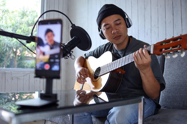 Influenceur asiatique jouant de la guitare lors d'un podcast ou d'une diffusion vidéo en direct pour le public de la foule