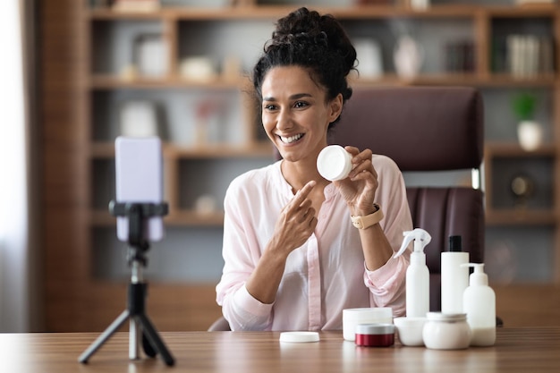 Photo influenceur beauté séduisante jeune femme en streaming depuis la maison montrant des cosmétiques