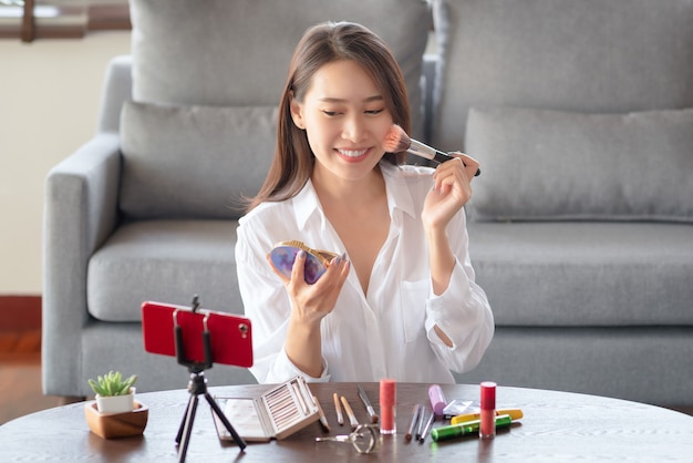 Influenceuse asiatique de beauté faisant un didacticiel vidéo pour sa chaîne de beauté sur les cosmétiques pendant que vous restez en sécurité à la maison