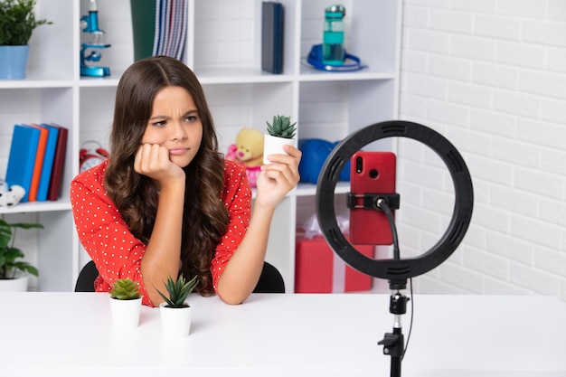 L'influenceuse blogueuse adolescente utilise une lampe à led selfie et un smartphone sur un trépied pour créer un didacticiel vidéo en ligne