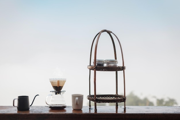 Infusion de café arabica par un équipement d'égouttement de café vintage situé sur une table en bois le matin avec un fond de montagne et de nature