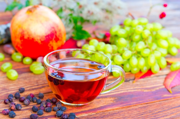 Infusion De Fruits D'aubépine Sur Le Fond De Raisins Blancs, De Grenades Et De Feuilles D'automne