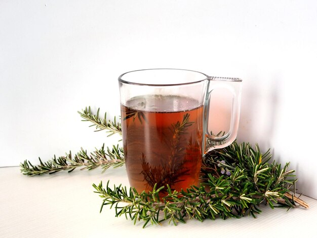 Infusion de romarin ou thé dans une tasse transparente et branches de romarin isolées sur fond blanc