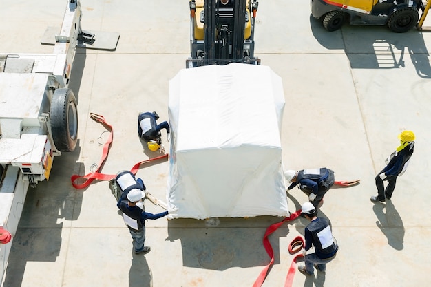 L&#39;ingénierie avec des casques de sécurité prépare une machine avant la grue industrielle