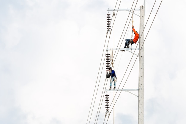 Ingénierie des hommes asiatiques travaillant sur le champ de travail haute tension à la campagne