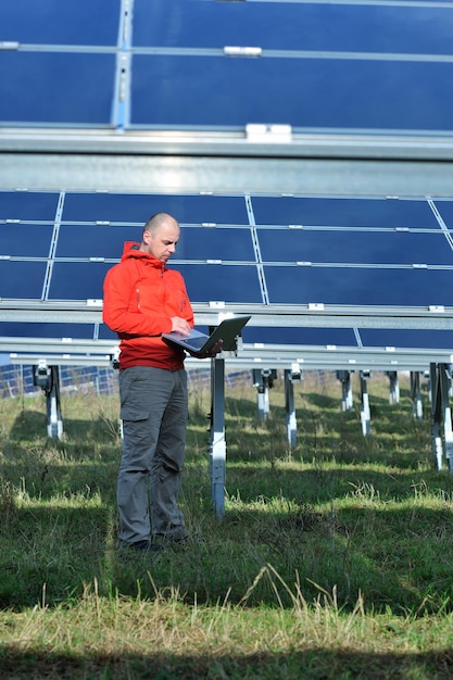 ingénieur d'affaires utilisant un ordinateur portable à l'usine de panneaux solaires champ d'énergie écologique en arrière-plan
