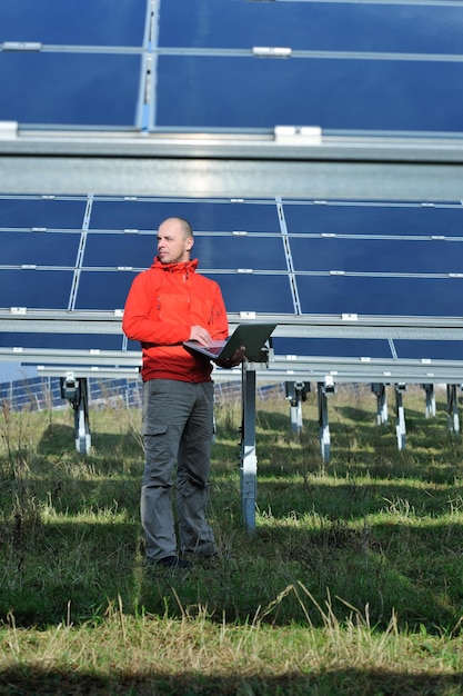 ingénieur d'affaires utilisant un ordinateur portable à l'usine de panneaux solaires champ d'énergie écologique en arrière-plan