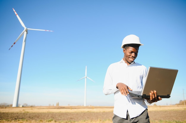 Ingénieur africain debout et tenant un ordinateur portable avec éolienne