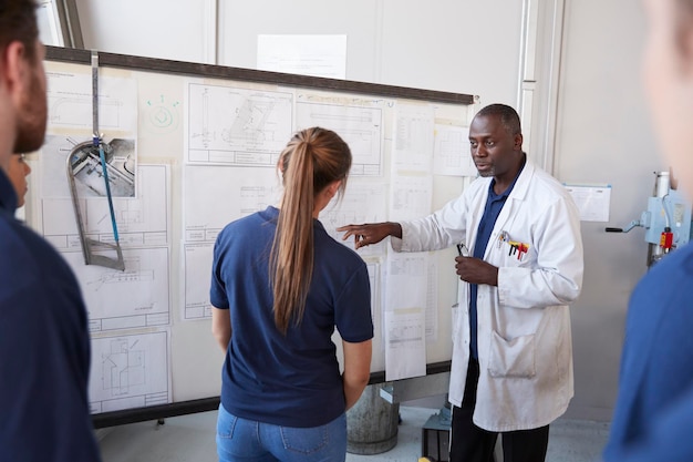 Ingénieur avec apprenti au tableau blanc devant le groupe